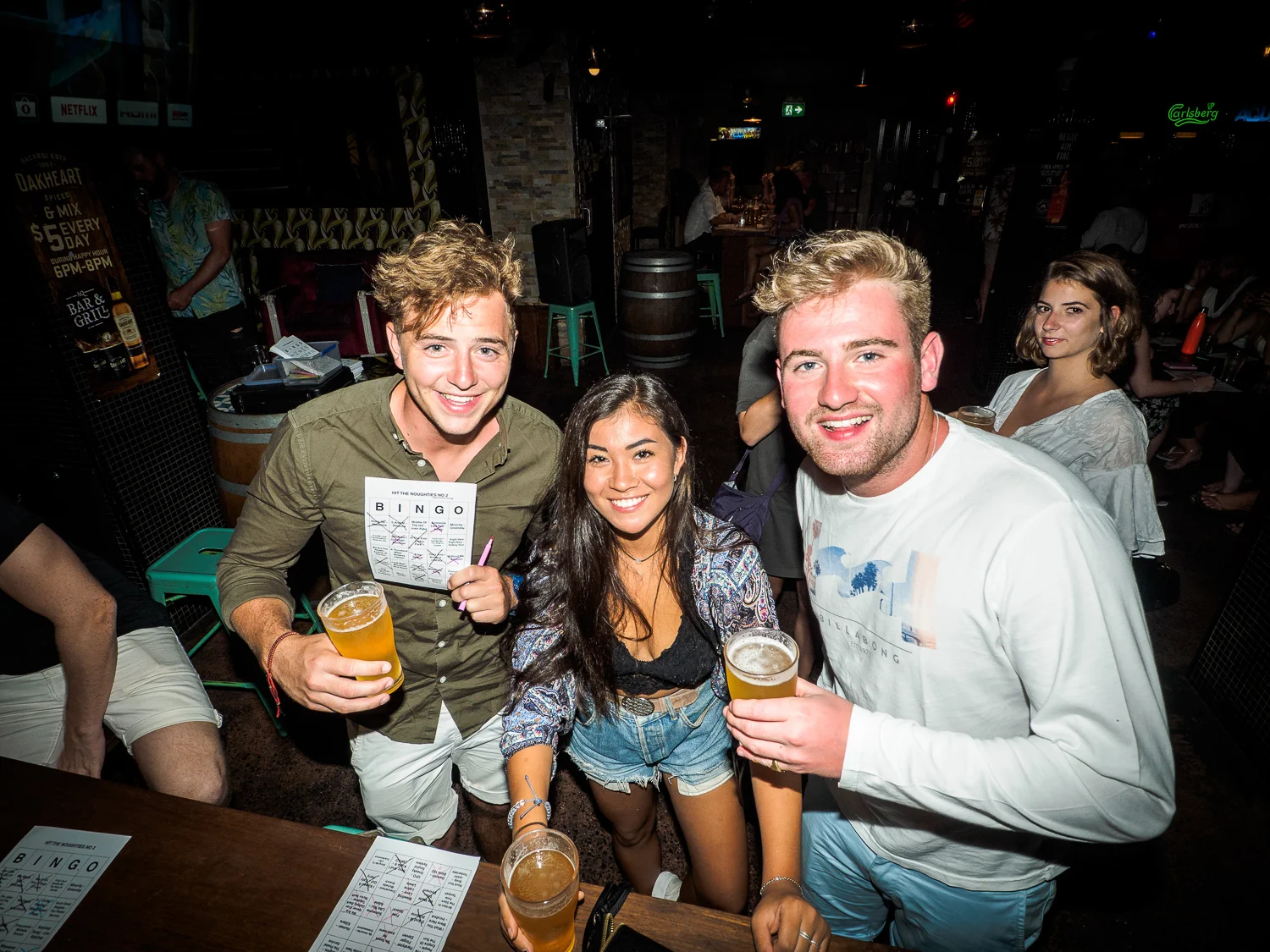 Friends holding a music bingo card at a pub